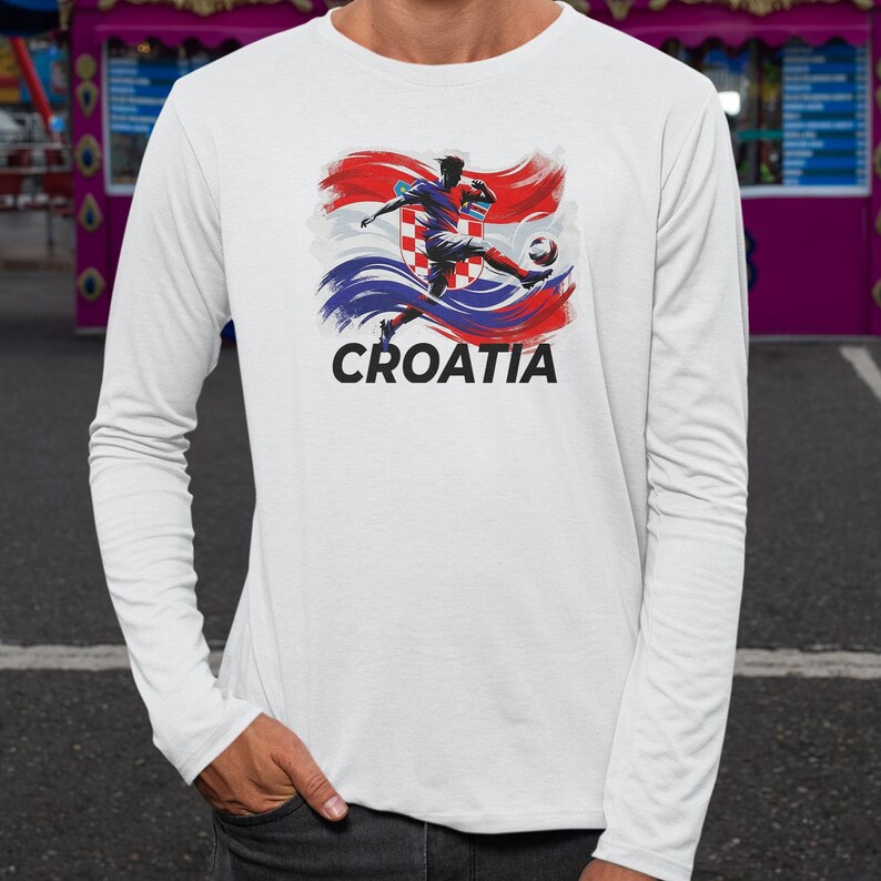 A white long-sleeved t-shirt with a graphic design depicting a soccer player kicking a ball, along with the word "Croatia" written below the image.