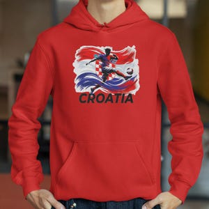A red hoodie with a graphic of a soccer player kicking a ball, along with the word "Croatia" printed on it.