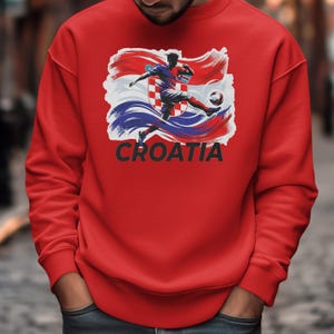 A red sweater with a graphic design depicting a soccer player kicking a ball, along with the word "Croatia" written below.