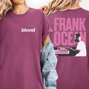 A person wearing a purple t-shirt with the text "blond" and a graphic of a person playing a keyboard.