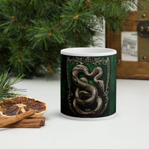 Silvermugg med heraldisk orm – Medeltida ormemblem på grön bakgrund