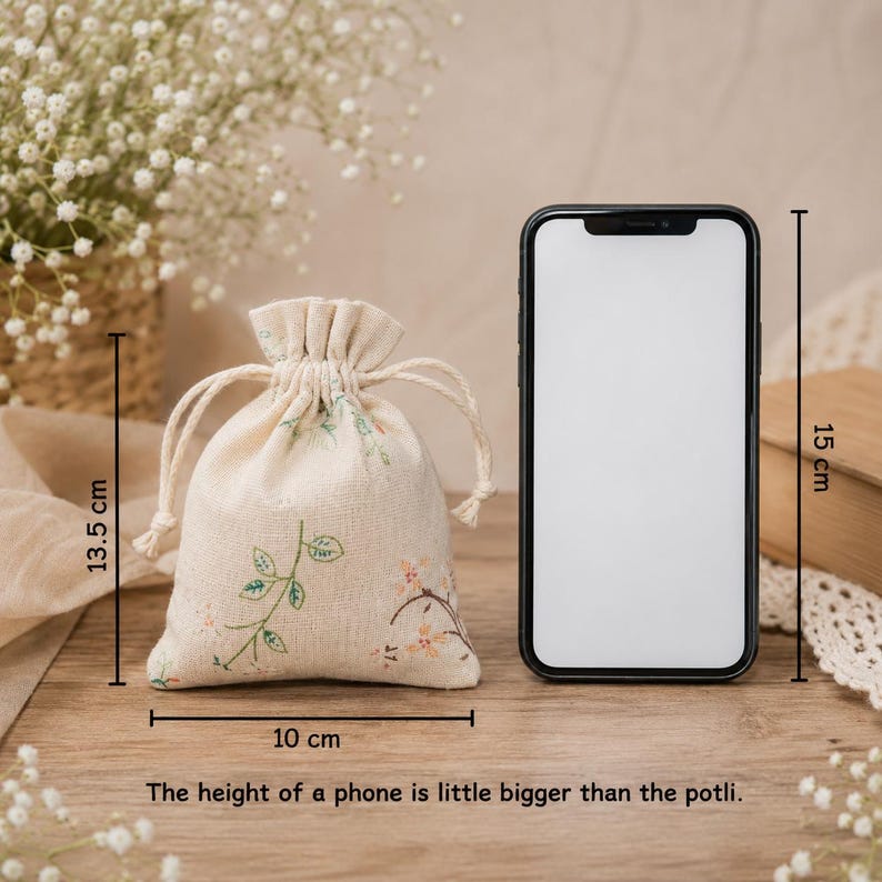 May include: A beige drawstring pouch with a floral pattern, measuring 13.5 cm in height and 10 cm in width, positioned next to a smartphone that is 15 cm tall. The text states: The height of a phone is little bigger than the potli.