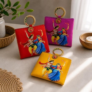 Può includere: Tre borse quadrate colorate, rosse, viola e gialle, con manici dorati. Ogni borsa presenta una stampa di figure danzanti in giallo, blu e rosso. I manici sono adornati da dettagli dorati.