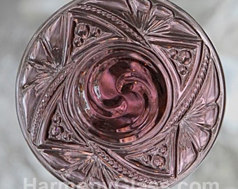 May include: A clear glass dish with a swirling pattern in the center and a geometric design around the edge. The dish is a deep purple color.