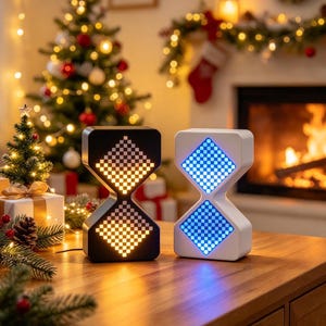 May include: Two hourglass-shaped digital clocks with pixelated displays. The left clock is black with an orange light display, and the right clock is white with a blue light display. Both devices feature a geometric, dual-diamond screen layout.
