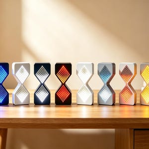 Peut inclure: Une rangée de huit horloges numériques en forme de sablier avec des écrans à motifs de grille. Chaque unité présente une couleur unique, notamment bleu, blanc, rouge et jaune, avec des effets de lumière dégradés sur les sections en losange.