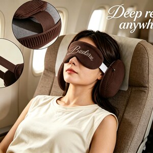 May include: A brown corduroy sleep mask with the embroidered text "Beature" and integrated side ear cushions. The mask features a wide elastic strap for secure placement, designed to cover the eyes and ears for light and sound reduction.