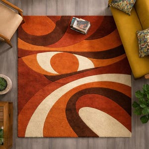 May include: A retro-style area rug with an abstract design in shades of orange, brown, and cream. The rug features curved lines and circular shapes, creating a bold, eye-catching pattern. The rug is rectangular and appears to be made of a soft, textured material.