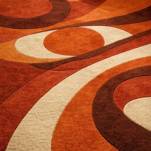 May include: A close-up of a retro-style rug with a swirling pattern. The rug features a combination of warm colors, including shades of orange, brown, and cream. The design is composed of curved lines and circular shapes, creating a textured, eye-catching surface.