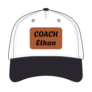 Könnte beinhalten: Eine weiße Baseballkappe mit schwarzem Schirm. Die Kappe hat ein braunes rechteckiges Patch mit den Worten "COACH Ethan" in schwarzer Schrift. Auf der Oberseite befindet sich ein schwarzer Knopf.