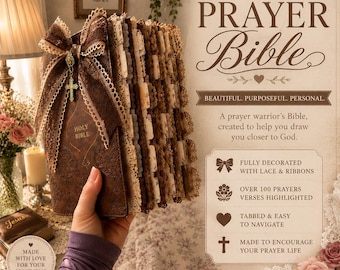 May include: A brown leather-bound Holy Bible decorated with brown lace ribbons and a small cross charm. The book features numerous tabbed pages with floral patterns and lace edges. Text on the cover includes DECORATED PRAYER BIBLE and other descriptive phrases about its features.