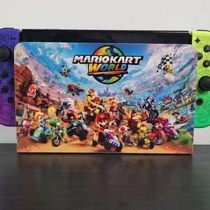 Op de afbeelding: Een Nintendo Switch-console met een aangepaste skin met personages en voertuigen uit de Mario Kart World-videogame. De Joy-Con-controllers zijn paars en groen. De skin heeft het Mario Kart World-logo.