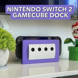 May include: A purple Nintendo Switch 2 GameCube dock with a white GameCube controller port panel. The dock is designed to hold a Nintendo Switch console. The text "NINTENDO SWITCH 2 GAMECUBE DOCK" is displayed in a purple banner.