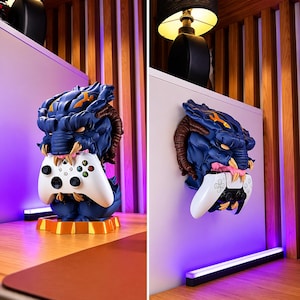 Può includere: Un supporto per controller a tema drago blu e oro con un controller Xbox bianco. Il supporto è su una base dorata. Il drago ha corna marroni e una lingua rosa. Il controller è tenuto nella bocca del drago.