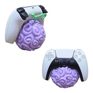 May include: Two white and black PlayStation 5 controllers are shown with a purple, swirled fruit design. The fruit has a green stem. The controllers are positioned to appear as if they are holding the fruit.
