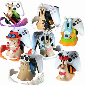 May include: A collection of colorful snail-shaped controller holders, each paired with a white Xbox or PlayStation controller. The snail designs feature various character-inspired themes, with vibrant colors and detailed expressions. These holders add a unique touch to gaming setups.