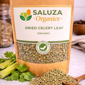 Puede incluir: Una bolsa de papel marrón de hojas de apio secas con la marca "SALUZA Organics" impresa en la parte delantera. La bolsa tiene una ventana transparente que muestra las hojas secas. Un pequeño montón de hojas de apio secas y una cuchara de madera están delante de la bolsa.