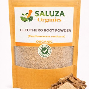 Può includere: Una confezione di polvere di radice di eleuthero, con il marchio "SALUZA Organics" in verde e arancione. La confezione è beige con una finestra trasparente che mostra la polvere. Un piccolo mucchio di polvere e alcuni pezzi di radice sono davanti alla confezione.