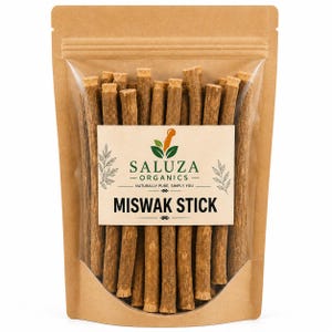 Op de afbeelding: Een bruine kraftpapieren zak met een doorzichtig venster met daarin meerdere lichtbruine Miswak-stokjes. Het etiket bevat de tekst SALUZA ORGANICS NATURALLY PURE, SIMPLY YOU en MISWAK STICK met een groen blad en oranje vijzel-icoon.
