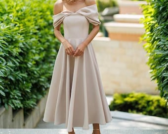 Vestido midi beige con hombros descubiertos, corte en A, elegante atuendo de invitada de boda para noche.