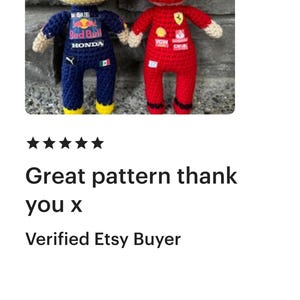May include: Two crocheted dolls representing race car drivers. The left doll wears a yellow helmet and a dark blue racing suit with Red Bull and Honda branding. The right doll wears a red helmet and a red racing suit with Ferrari branding.