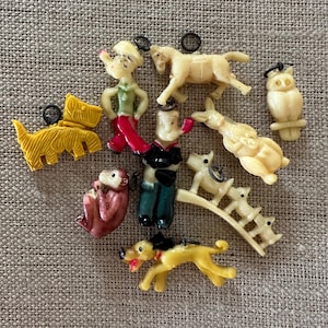 May include: A selection of vintage plastic animal ornaments in various colours. Includes a yellow dog, monkey, owl, horse, and a figure in a sailor outfit. Each ornament has a small metal loop for hanging.