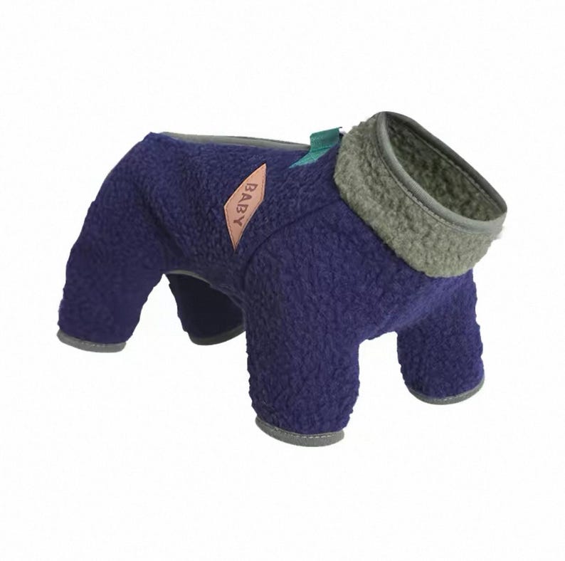 May include: A navy blue dog coat with a gray collar and trim. The coat has a soft, textured appearance and features a small pink label with the word "BABY" on it. The coat is designed to cover the dog's body and legs.
