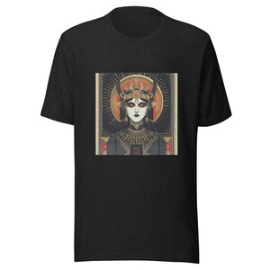 Peut inclure: T-shirt gris foncé avec un graphisme détaillé d'une femme portant une couronne et un col orné. L'œuvre d'art a un style vintage, art déco avec des accents dorés, rouges et noirs. Le motif est centré sur le t-shirt.