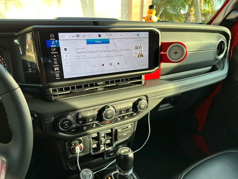 Puede incluir: Interior del salpicadero de un coche con una gran pantalla de informaci&oacute;n que muestra informaci&oacute;n musical. La pantalla muestra la canci&oacute;n "Twelve Days of Christmas". Un peque&ntilde;o patito de goma est&aacute; sentado en el salpicadero.