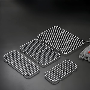 Peut inclure: Un ensemble de quatre grilles de refroidissement rectangulaires en métal argenté de tailles variées, chacune dotée d'un motif en grille de fils métalliques fins et de petits pieds surélevés aux coins pour surélever la grille.