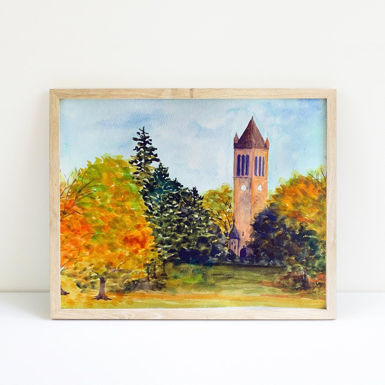 K&ouml;nnte beinhalten: Aquarellgem&auml;lde eines hohen Ziegelturms mit einem Zifferblatt, umgeben von B&auml;umen mit Herbstlaub. Der Turm steht vor einem blauen Himmel mit wei&szlig;en Wolken.