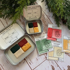 Puede incluir: Un juego de seis acuarelas en una lata de metal. Los colores son verde pino, baya, crema, oro y dos tonos de verde. La lata tiene una etiqueta que dice "The Hare Painter - Acuarela hecha a mano Paleta de Navidad festiva".