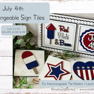 May include: Interchangeable sign tiles for a July 4th themed decor. The tiles feature a red, white and blue colour scheme with designs like a star, a heart, a popsicle and a circle with the text "July 4th".