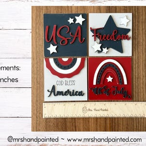 May include: A wooden patriotic decoration with four square blocks. Each block features red, white, and blue designs with the words "USA", "Freedom", "God Bless America", and "4th of July". The item measures 4.252 inches.
