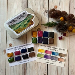 May include: A set of handmade watercolor paints in a tin with a label that says "Iowa Prairie". The paint colors are: Ox Eye, Cardinal Flower, Prairie Sky, Bur Oak, Prairie Dropseed, Blazingstar, Reakirt's Blue, Wild Rye.