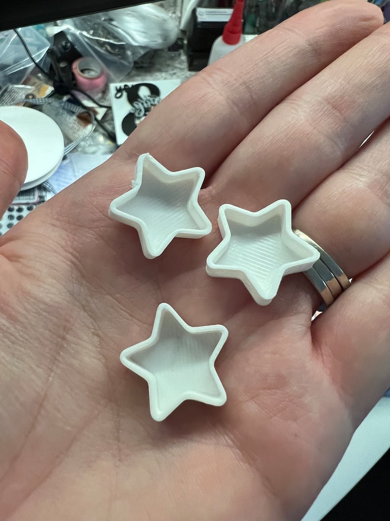 Pode incluir: Tr&ecirc;s moldes brancos em forma de estrela, provavelmente para fundi&ccedil;&atilde;o de resina ou outros projetos de artesanato.