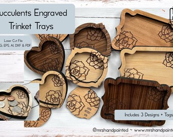 May include: Three wooden trinket trays with succulent designs. The trays are in the shapes of a heart, a rectangle, and a rounded rectangle. The trays are laser cut and engraved with a succulent design. The text "Includes 3 Designs + Tags" is visible in the image.