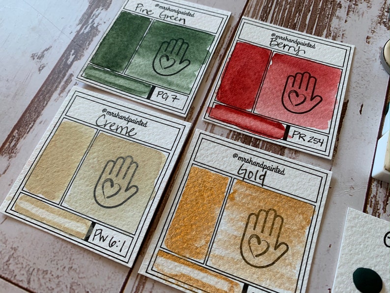 Puede incluir: Cuatro muestras de pintura acuarela con muestras de color pintadas a mano y los n&uacute;meros de pigmento correspondientes. Los colores son Verde pino (PG7), Crema (PW6:1), Baya (PR 254) y Oro.