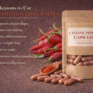 Puede incluir: Un paquete de cápsulas de pimienta de cayena con una ventana transparente, rodeado de chiles rojos. Una cuchara de madera contiene polvo de pimienta de cayena. El texto en el paquete dice "Cayenne Pepper Capsules".