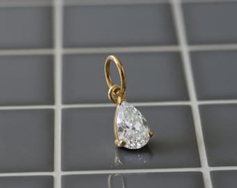Può includere: Ciondolo in oro con diamante a goccia. Il diamante è incastonato in una lunetta d'oro e ha un taglio brillante. Il ciondolo è sospeso a un anello d'oro, ideale per una collana o un braccialetto.