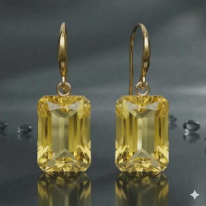 Puede incluir: Un par de pendientes colgantes dorados con grandes piedras preciosas amarillas rectangulares. Las piedras preciosas facetadas capturan la luz, creando un efecto brillante. Diseño simple y elegante.