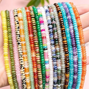 Puede incluir: Una colección de múltiples hilos de pequeñas cuentas de piedras preciosas redondas y pulidas en una variedad de colores, incluyendo amarillo, verde, rosa, jaspe dálmata, naranja, rojo, blanco, azul, morado y marrón, en filas paralelas.