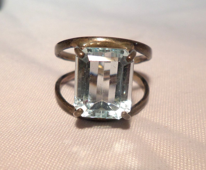 May include: A silver ring with a large, clear, rectangular aquamarine gemstone.