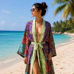 May include: A long, open-front kimono robe featuring a vibrant patchwork design with various floral and geometric patterns in shades of purple, green, red, and blue. The garment includes wide sleeves, a matching tie belt, and a light green trim.