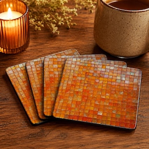 May include: A set of four square coasters featuring a mosaic pattern of small, iridescent tiles in shades of orange, yellow, and amber. Each coaster has a smooth, flat surface with a grid-like arrangement of reflective, multi-coloured glass squares.