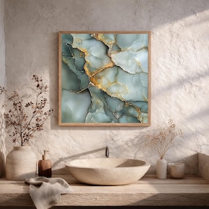 May include: A framed abstract art print featuring a marble-like design in shades of teal, gold, and white. The artwork is displayed in a bathroom setting, above a stone sink and wooden countertop. The frame is made of light-colored wood.