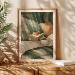 Pu&ograve; includere: Una stampa artistica incorniciata raffigura una scena accogliente di un piccolo criceto che legge un libro a letto. L'opera presenta una coperta a righe verdi e bianche, un cuscino beige e una tazza di caff&egrave; bianca. La stampa &egrave; esposta su una superficie di legno.