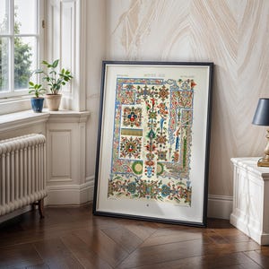 Pode incluir: Uma impressão emoldurada de uma ilustração de manuscrito medieval, com padrões intrincados em vermelho, azul, verde e dourado. A obra de arte é exibida em uma sala com uma janela, plantas e uma pequena lâmpada em uma mesa lateral. A moldura é preta.