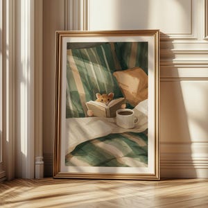 Pu&ograve; includere: Una stampa artistica incorniciata raffigura un criceto che legge un libro a letto. L'opera d'arte presenta una cornice dorata, una coperta a righe verdi e bianche, un cuscino beige e una tazza di caff&egrave; bianca. L'estetica generale &egrave; calda e invitante.