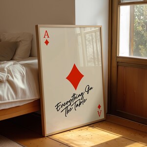 Può includere: Stampa artistica incorniciata con l'Asso di quadri. Il design presenta un grande simbolo di diamante rosso, la lettera "A" e la frase "Everything On The Table" in un carattere script. L'opera d'arte è esposta in una cornice di legno chiaro.